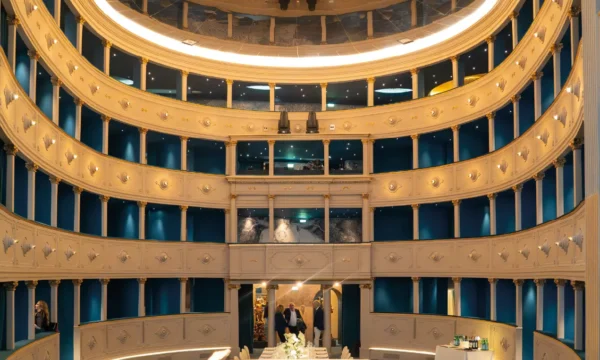 Vista frontale ad arco dei quattro ordini di palchi illuminati e della platea allestita per un evento al Teatro Nazionale di Firenze