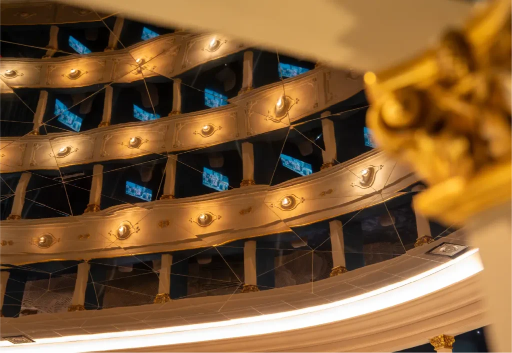 Riflesso geometrico dei palchi storici illuminati sulla superficie del soffitto del Teatro Nazionale di Firenze