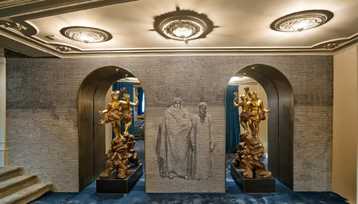Foyer del Teatro Nazionale di Firenze con sculture dorate nei portali ad arco, bassorilievo di Dante e Virgilio e rosoni illuminati a soffitto